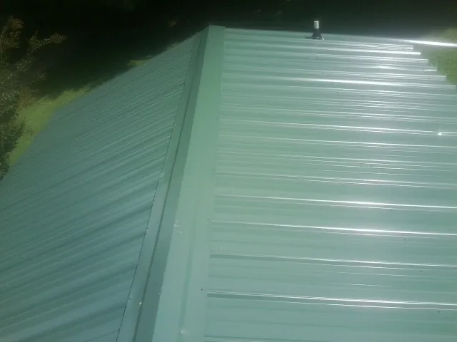 New green metal panels meeting at the ridge of a roof in Grove City