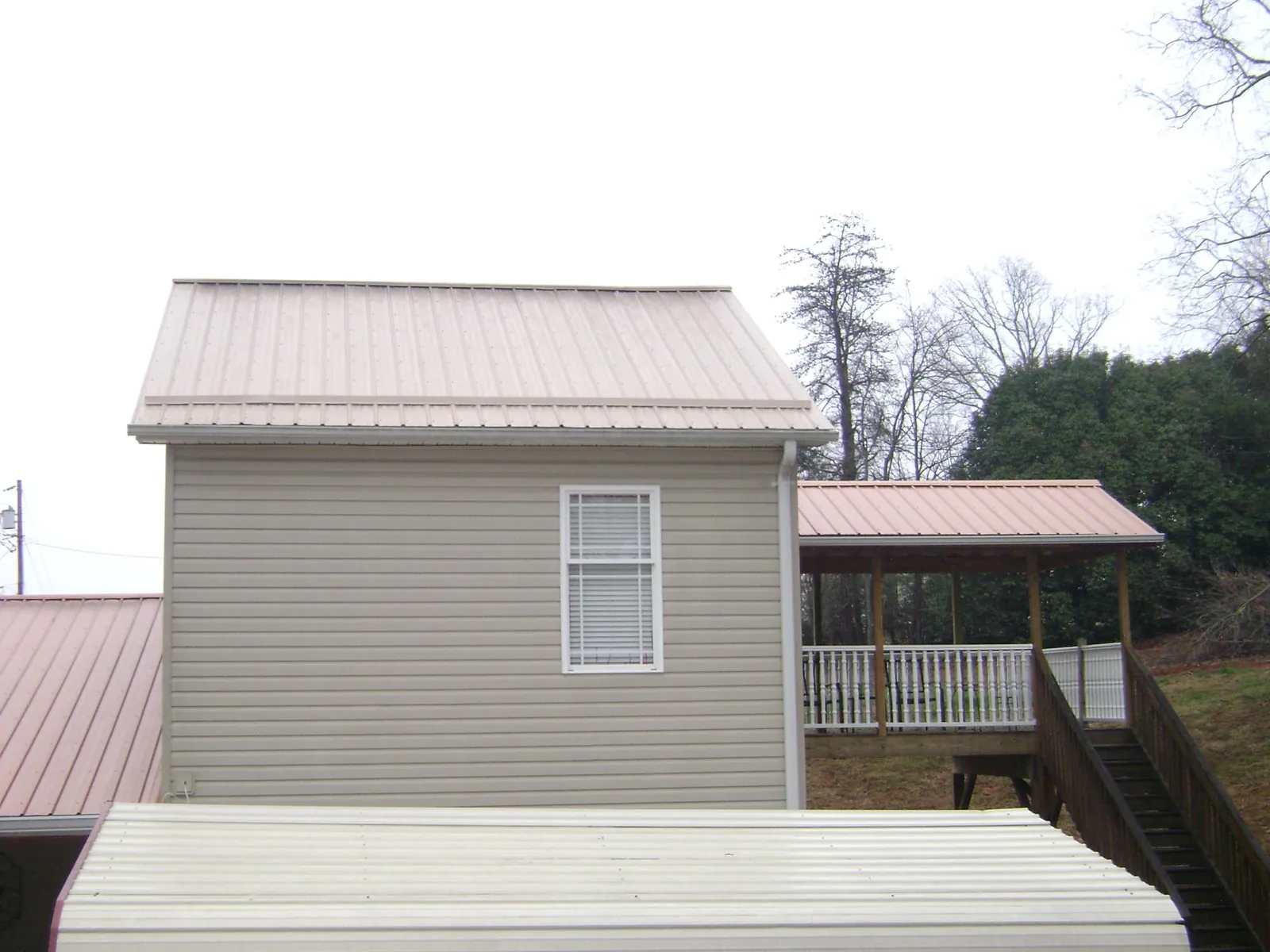 Tan metal roofs on a two story addition and attached porch, from a Roof Replacement job in Grove City